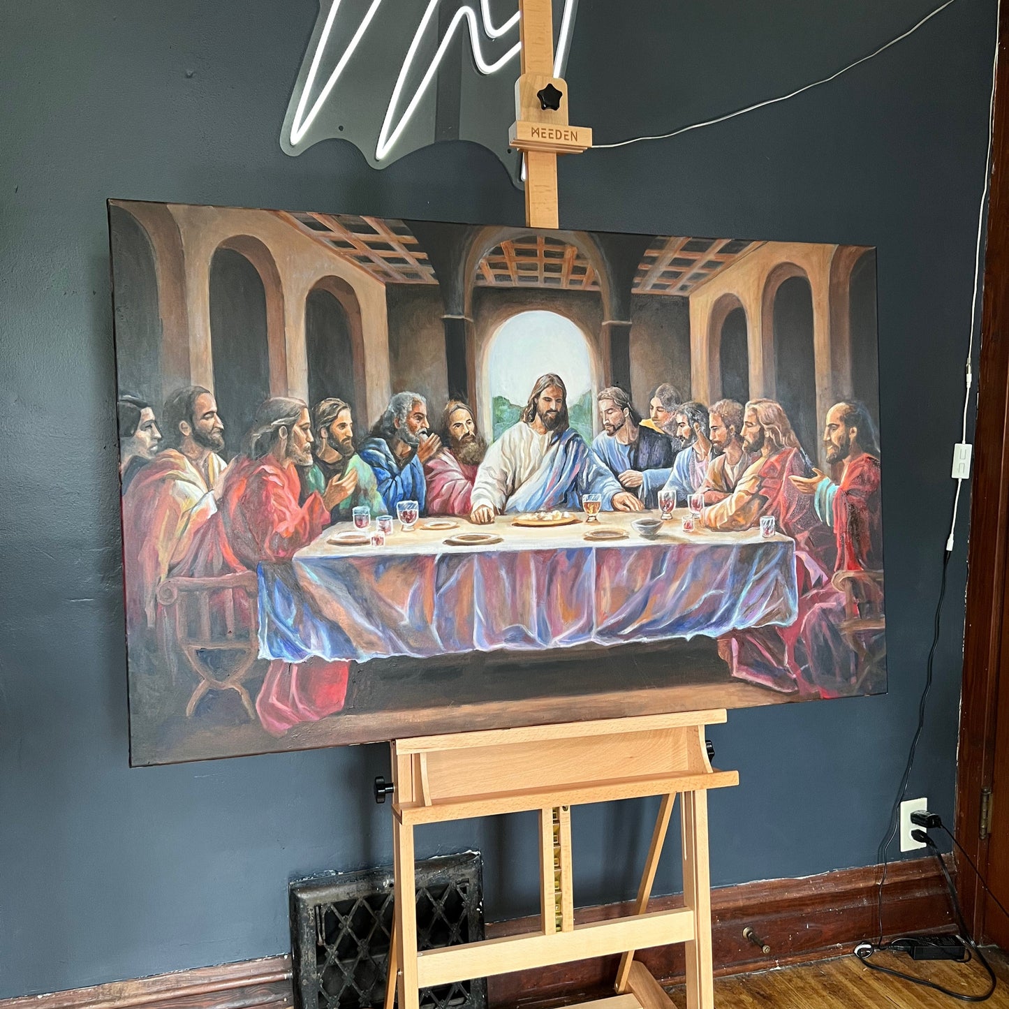 Painting of 'The Last Supper' on an easel against a dark wall.